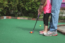 father and daughter playing mini golf 