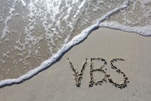 VBS written in the sand on a beach 