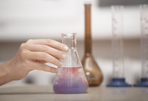 Hand of laboratory technician holding flask with chemical