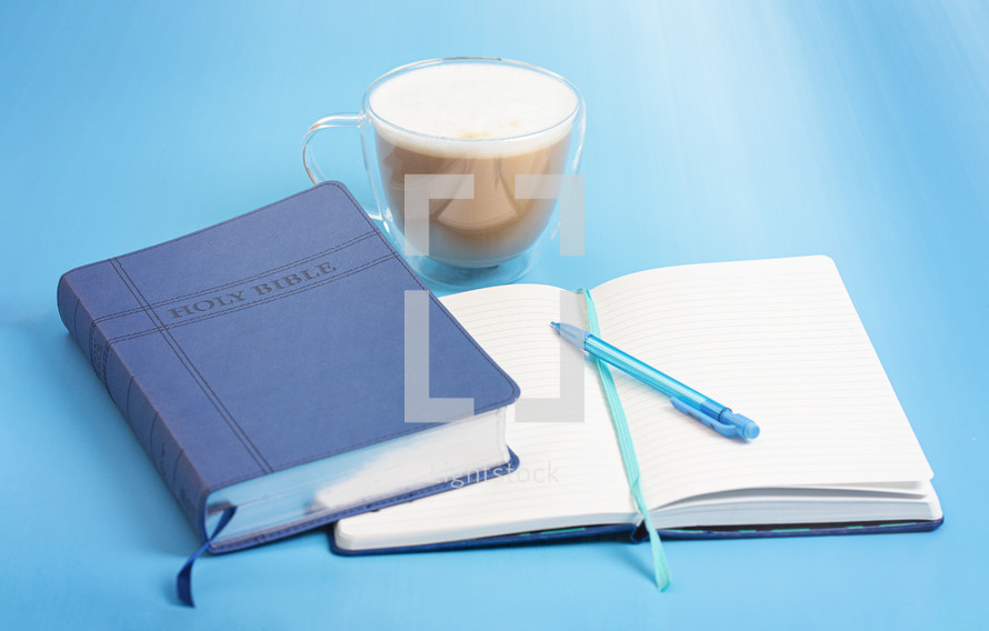 A Holy Bible with a Notebook to Study on a blue Background