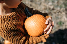 child holding a pumpkin 