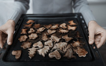 Woman holding baking tray with burnt cookies