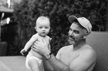 a father holding his infant son outdoors 
