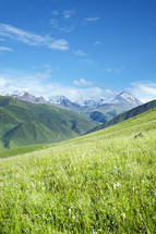 snow capped mountains and green rolling hills 