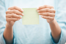 woman holding up a blank sticky note 