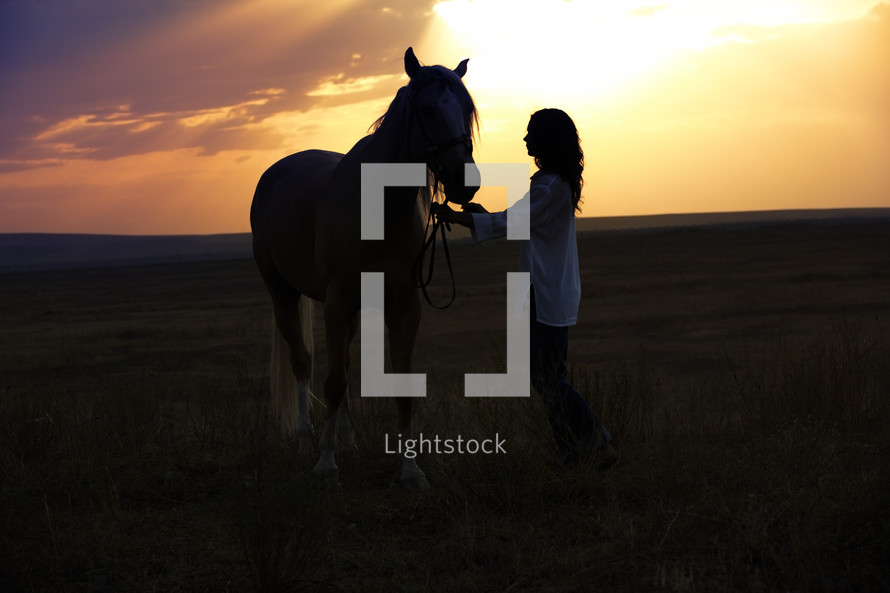 a woman and her horse at sunset 