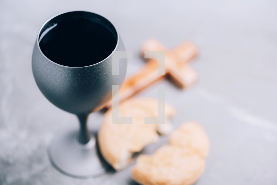 Communion still life. Unleavened bread, chalice of wine, silver kiddush wine cup on grey background. Christian communion concept for reminder of Jesus sacrifice. Easter passover