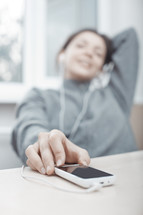 a woman listening to earbuds connected to a phone 