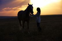 a woman and her horse at sunset 