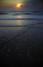 tide washing onto a beach at night 