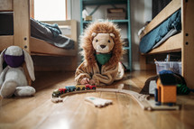 a toddler in a lion custom playing with toys on the floor 