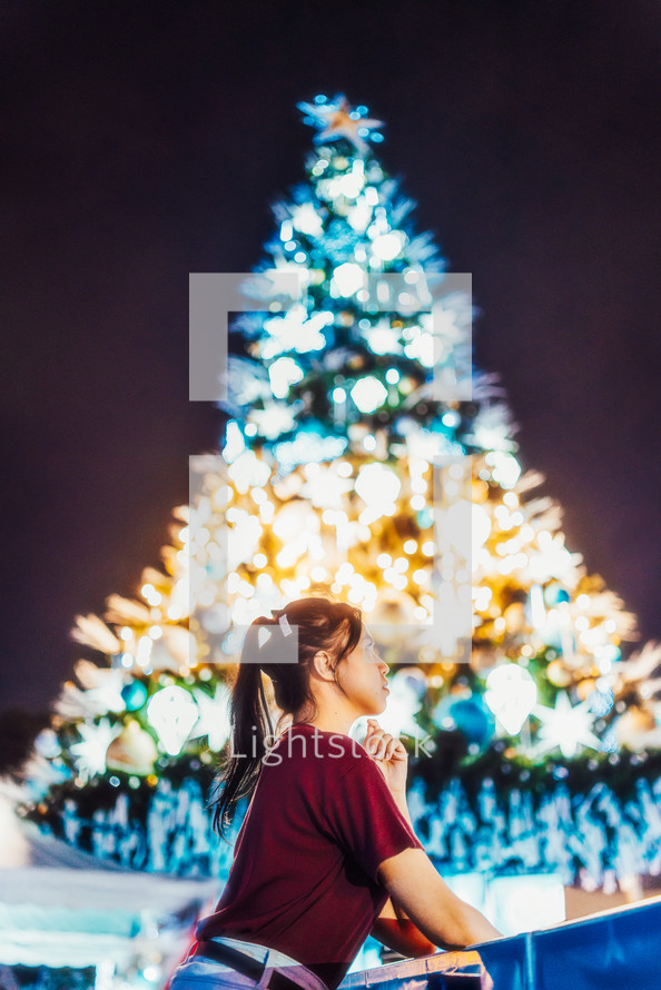 woman praying in front of a Christmas tree