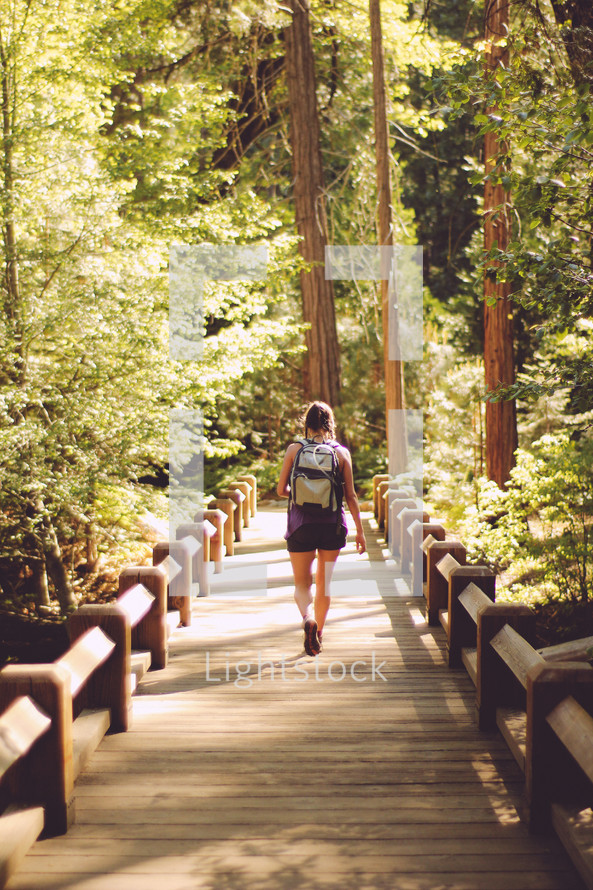 a woman hiking across a footbridge 