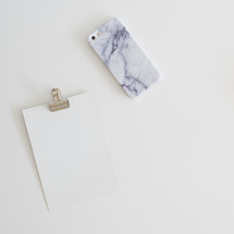 blank paper on a clip and granite patterned cellphone case 