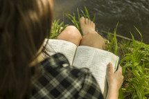 woman reading a Bible by a lake 