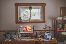 mistletoe hanging in a window above a messy desk 