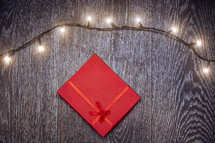 string of lights and red gift on a wood background 