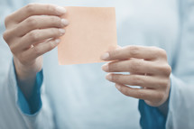 a woman holding up a blank sticky note 