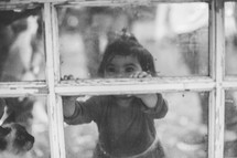 a toddler girl in a window 