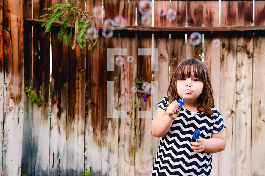 girl child blowing bubbles outdoors 