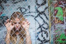 a woman clinging to a chain link fence