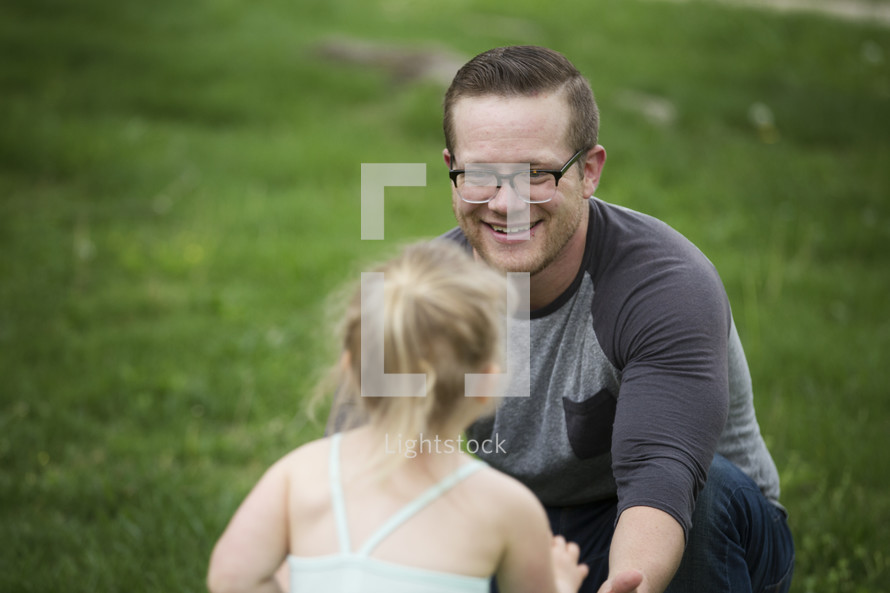 A father playing outdoors with his little daughter.