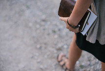 woman carrying a Bible and journal at her side 