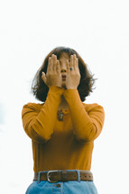a young woman covering her face with her hands
