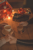 a couple holding hands near coffee mugs during the holidays 