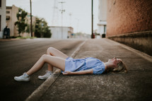 teen girl lying down on a sidewalk 
