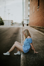 teen girl sitting on a curb 