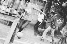 Young boys playing with a soccer ball in front of a house