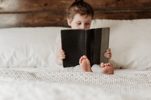 child reading a book in bed