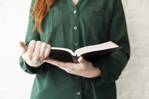 torso of a young woman reading a Bible 