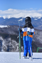 Carrying the Torch - Young Skier Treks Toward the Summit with Skis in Hand