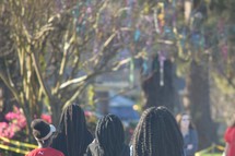 African American girls walking down a street with beads hanging from trees for Mardi Gras celebrations 