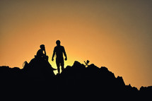 Silhouettes Of A Cyclists Standing on Cliff Against The Sun in Spring Time