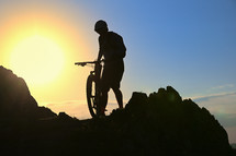 Silhouette Of A Cyclist Standing on Clif Against The Sun in Spring Time
