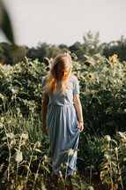 young woman standing in a field of sunflowers 