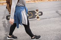 teen girl walking with a skateboard 