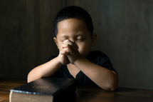 Asian child praying with his family