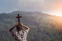 a boy holding a cross outdoors 
