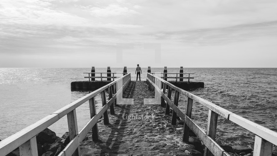 man standing at the end of a pier 