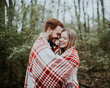 a couple wrapped up in a plaid blanket 