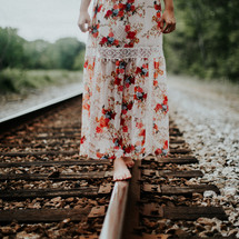 young woman balancing on train tracks