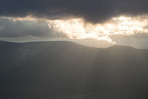 rays of sunlight shining through the clouds over mountains 