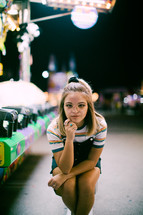 a teen girl standing next to a carnival ride 