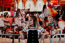 a girl standing in front of a carousel 