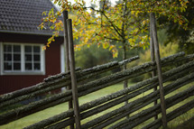 Rustic wood fence with red barn in background