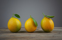 A row of three lemons in a row on a table.